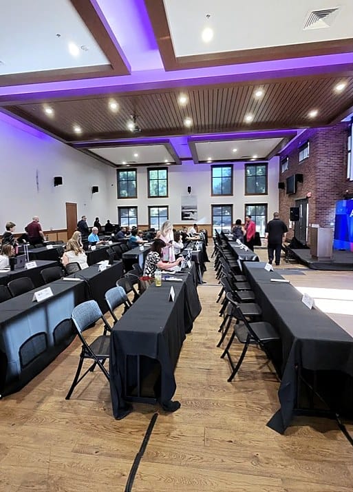 AI NOW Fresno attendees arriving at classroom-style tables under purple venue lighting