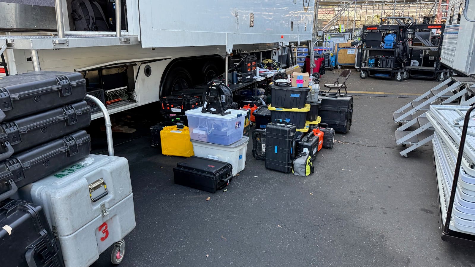 Broadcast equipment cases and production gear staged beside mobile units during Rose Parade load-in in Pasadena