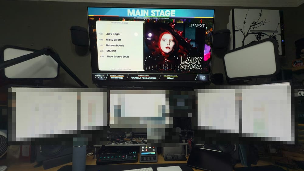 Coachella Main Stage feed above a multi-monitor production-network monitoring workstation, with private display details pixelated