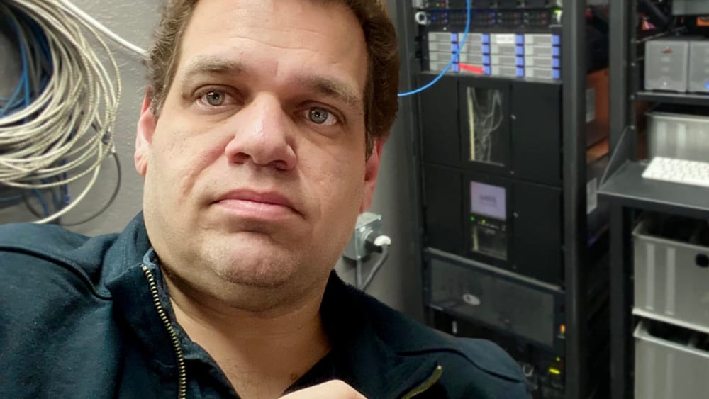 Thomas Fraley in a SetNet equipment room with network and production systems behind him