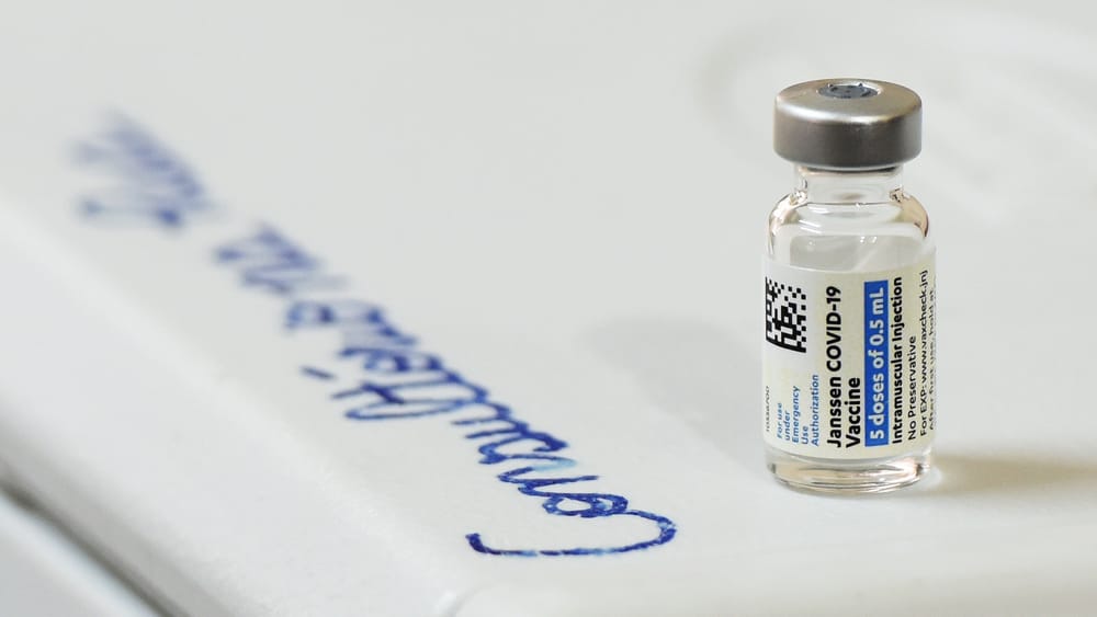 A vial of the Janssen COVID-19 vaccine on a white surface