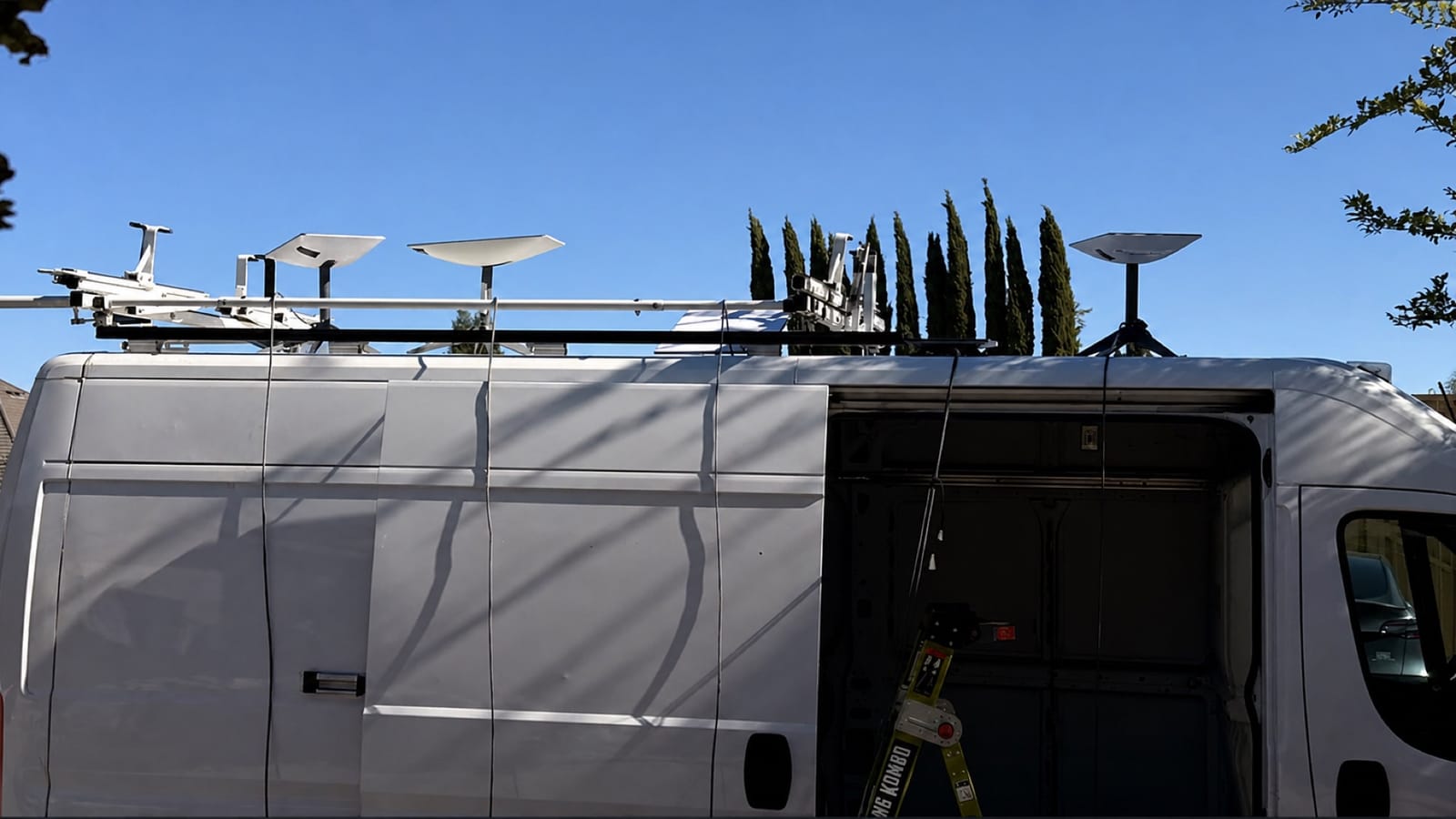 Five Starlink terminals mounted above a white production van during setup for AI NOW Fresno