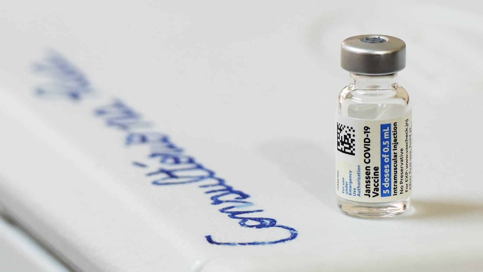 A vial of the Janssen COVID-19 vaccine on a white surface